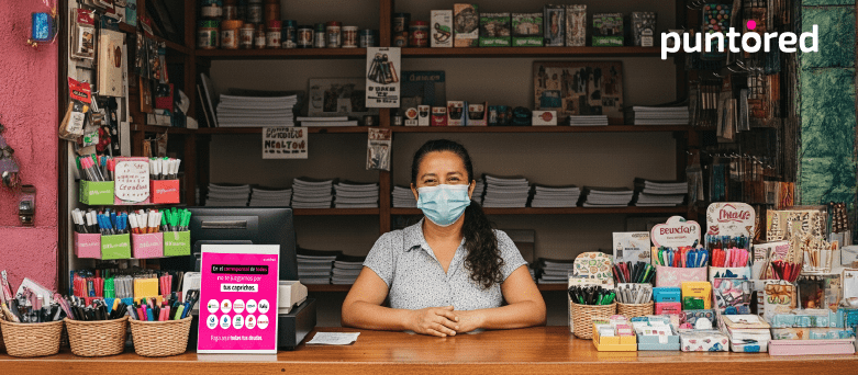 Tendera en una tienda de barrio con productos y punto de pagos transaccionales de Puntored